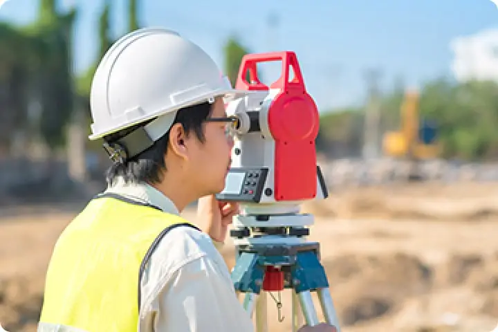 測量士が建設現場で測量をしている様子