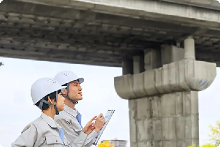 橋の下で作業員が手元の資料を見ながら確認している様子