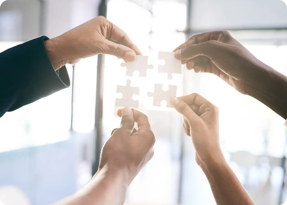 4人のスタッフがジグソーパズルをピースを持っている様子